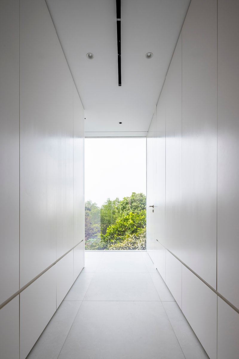 White corridor with full-height storage cabinetry terminating at a window framing treetops