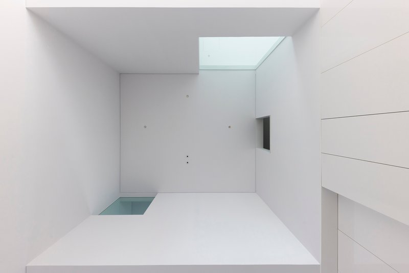 Looking up at white ceiling with recessed skylight and floating white panel above minimal floor outlet