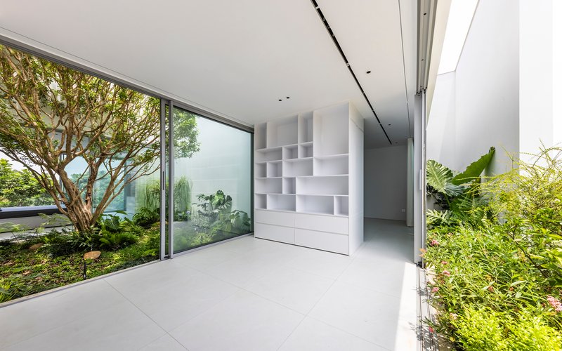Interior corridor with white modular shelving and full-height glazing framing a planted courtyard