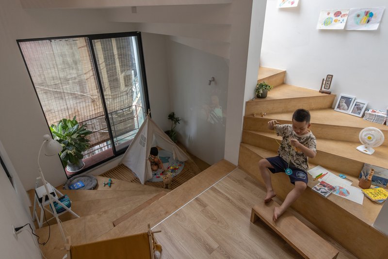 View down to the timber platform where a child sits drawing near a window