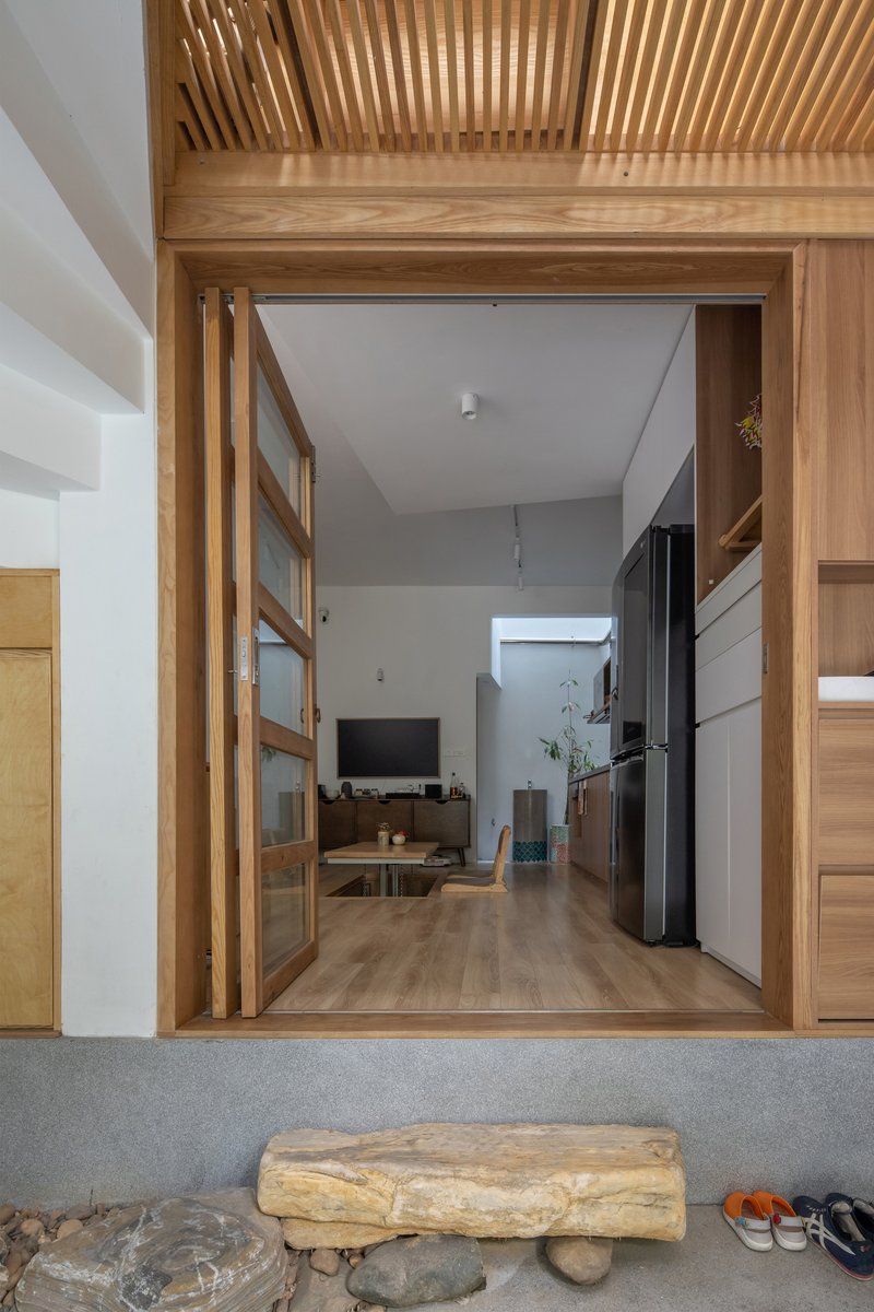 Threshold view through timber-framed sliding doors showing the slatted ceiling and living space beyond