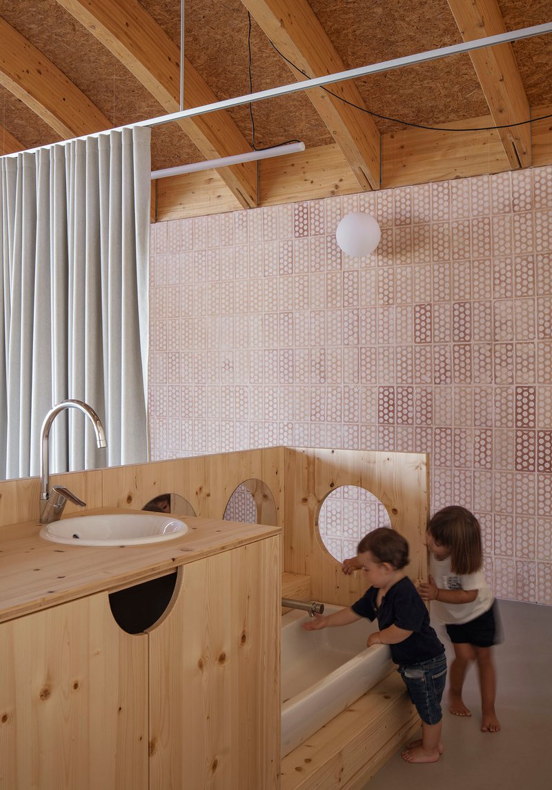 Timber bathroom vanity with circular mirrors and children using the facilities beneath a perforated panel wall