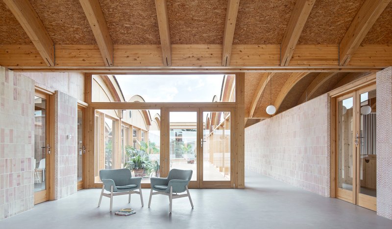 Interior room with exposed timber beams, hempcrete ceiling panels, and glazed doors opening to a courtyard