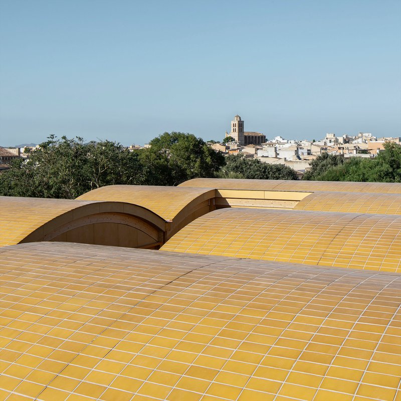 Rooftop view of the wave-form ceramic tile roof with a distant bell tower and village beyond
