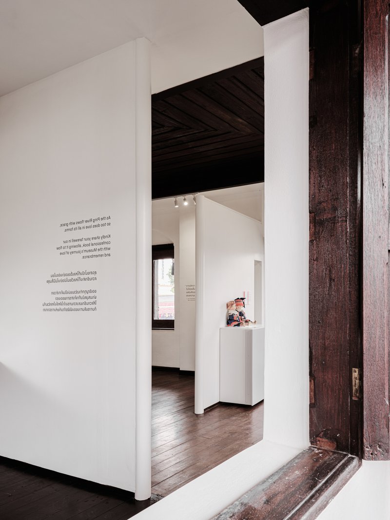 Doorway framed by weathered timber jamb leading to gallery spaces with exposed plank ceiling