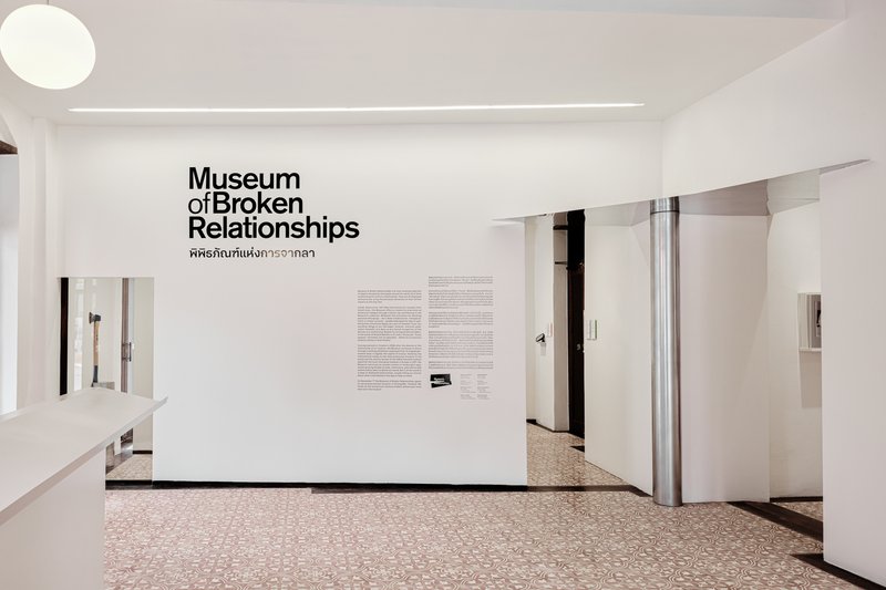 Exhibition entrance wall with black typography and descriptive text panels above terrazzo flooring