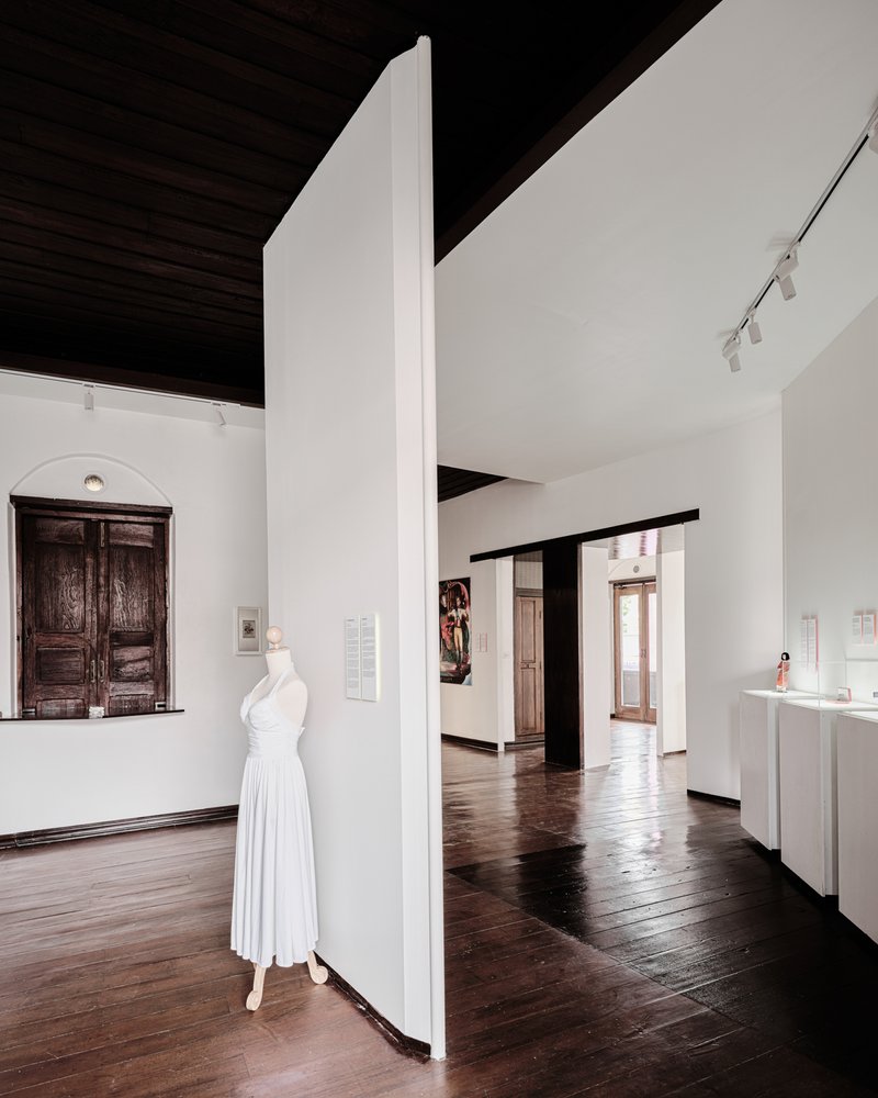 Freestanding white partition wall with a dress form displayed and dark timber ceiling above
