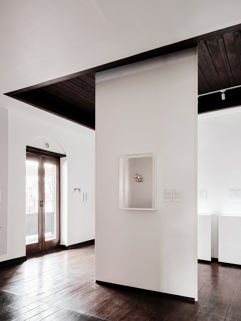 Framed artwork on a white partition wall with angular dark timber ceiling plane above
