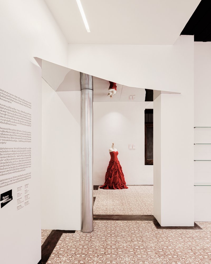 Angular metal column supporting folded ceiling planes above patterned terrazzo flooring