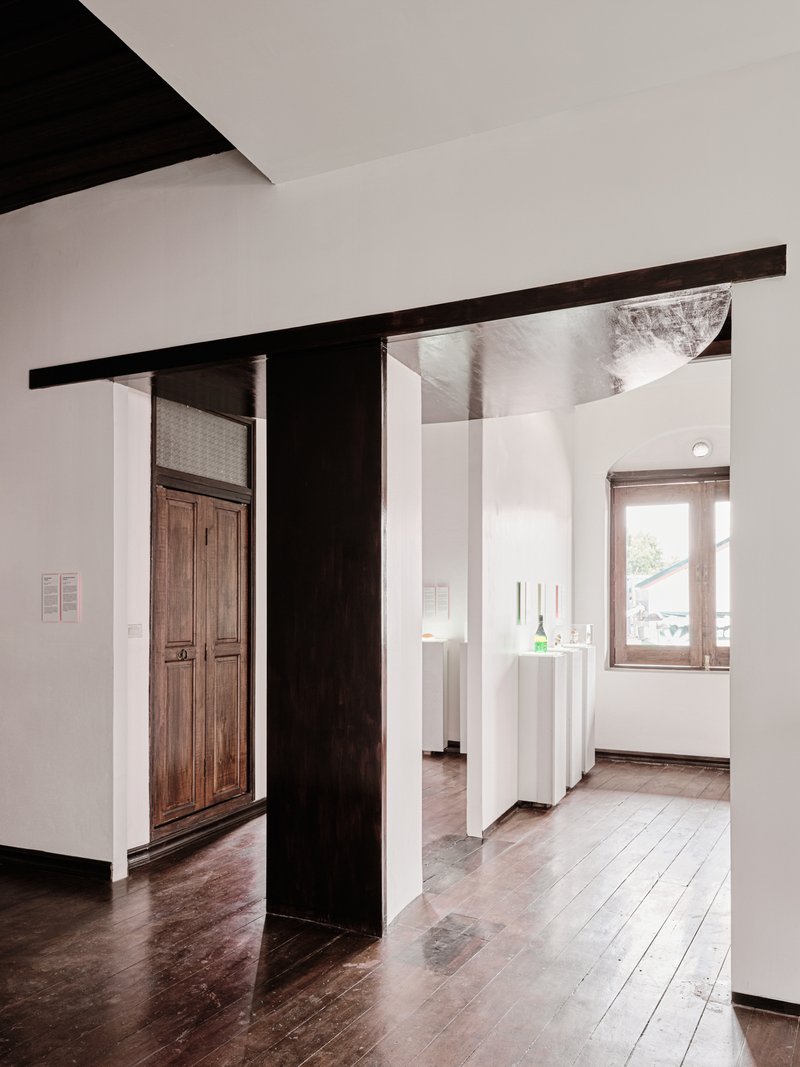 View through blackened steel frame into adjacent gallery rooms with timber door and window