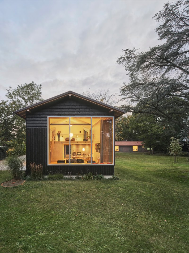 Gabled studio volume with full-height glazing and dark timber cladding at twilight
