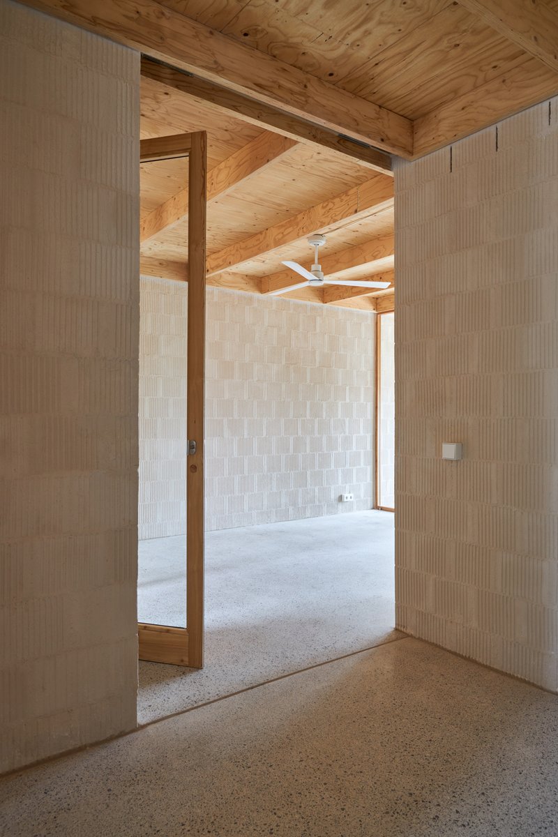 View through a timber-framed doorway into an adjacent room with white ceramic tile walls and ceiling fan above