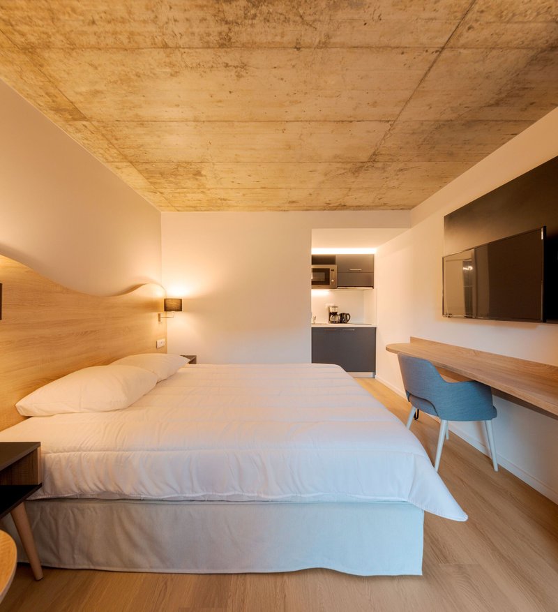 Guest room with exposed cross-laminated timber ceiling and integrated kitchenette niche