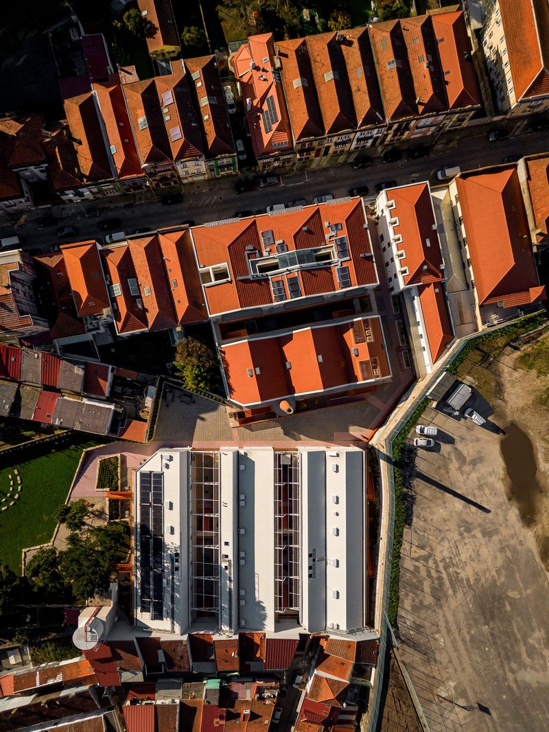Aerial view showing corrugated metal roof with central courtyard amid terracotta-tiled residential blocks