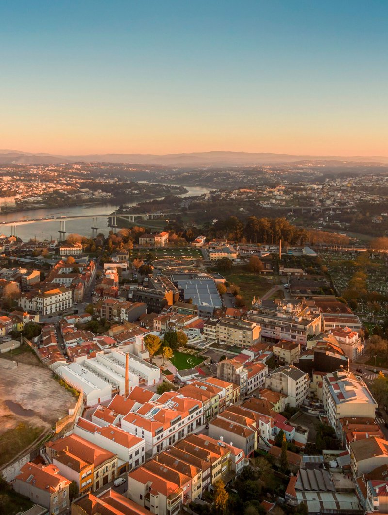 Aerial view of terracotta-tiled rooftops stretching across the urban fabric at golden hour