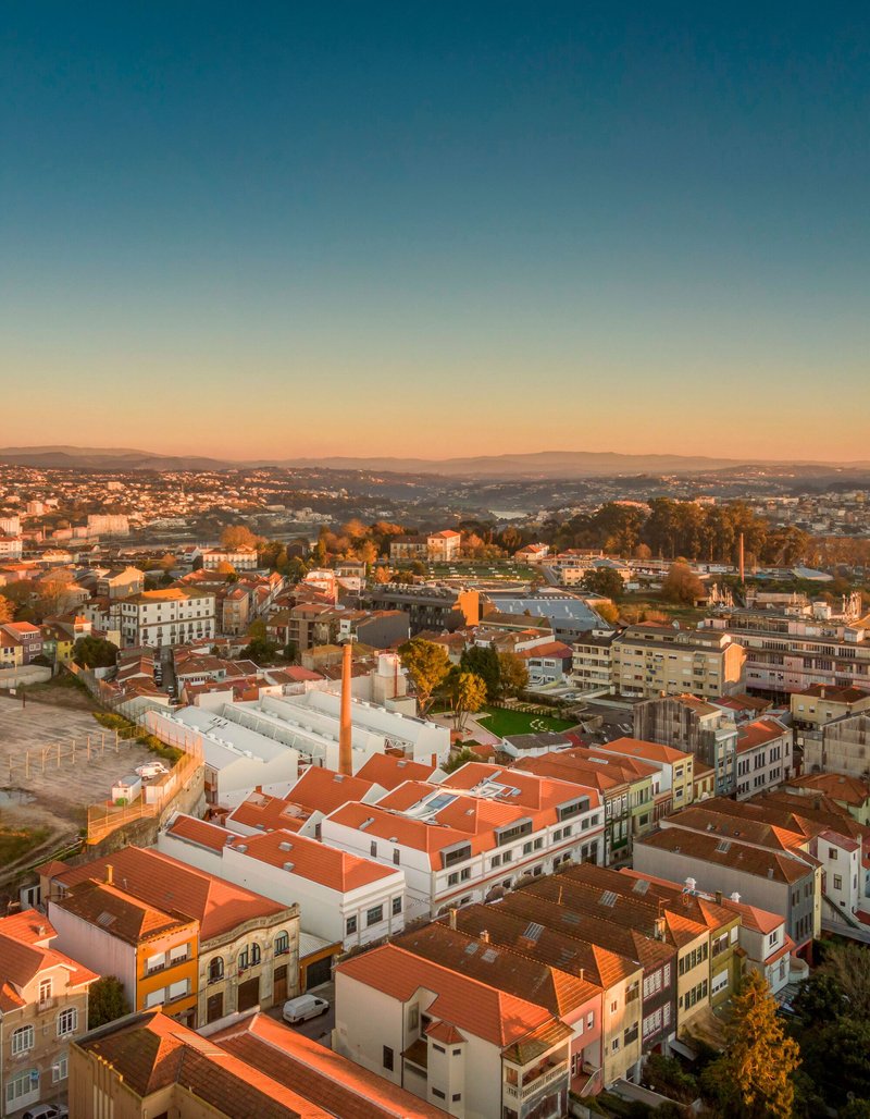Drone view of mixed-use buildings with terracotta roofs and white facades at sunset