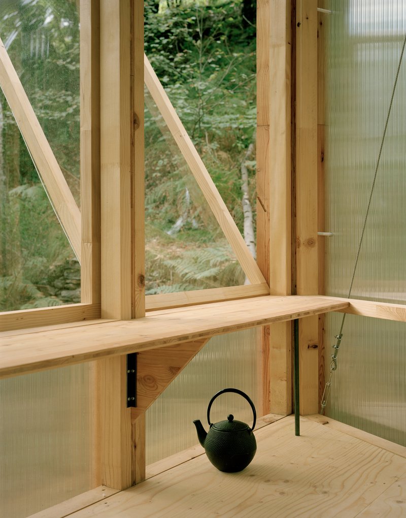 Corner detail showing diagonal timber bracing, plywood shelf and black cast iron teapot on the floor