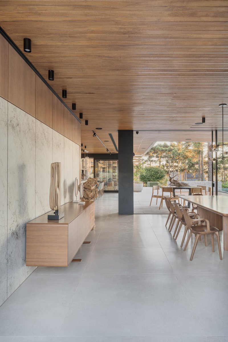 Open plan dining space with concrete floor and slatted wood ceiling extending toward glazed openings