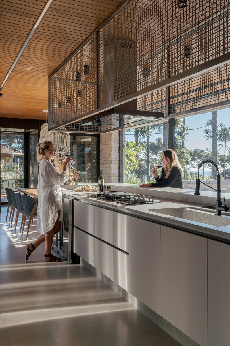 Kitchen island with two people preparing food beneath suspended mesh screen and glazed facade