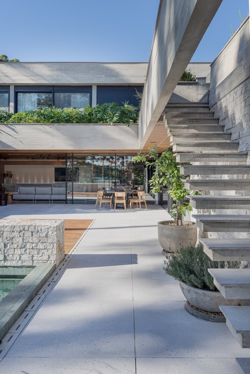 Cantilevered concrete staircase with planted risers overlooking covered terrace and pool edge