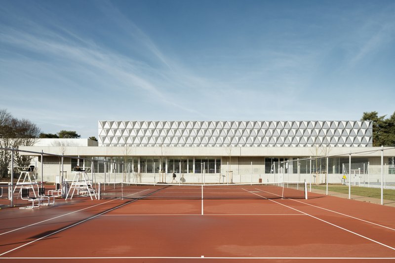Front elevation showing the triangulated roof screen above glazed perimeter and red clay tennis courts