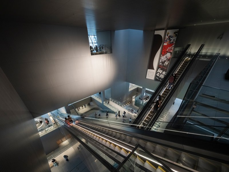 Escalators descending through the multi-story atrium with visitors on the lower level