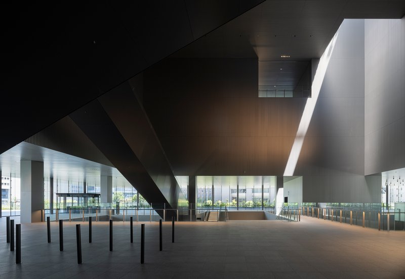 Ground level hall beneath a massive cantilevered ceiling slab supported by cylindrical columns