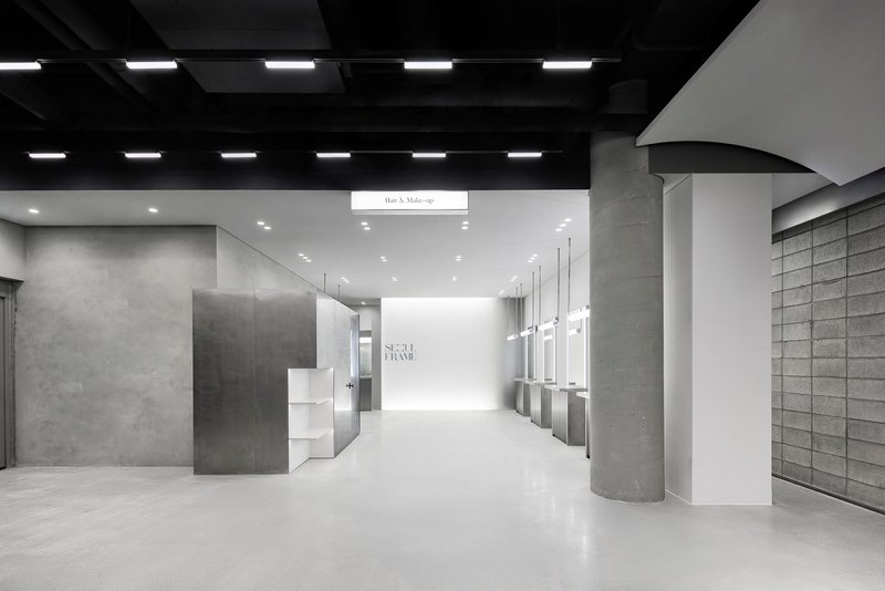 Retail corridor with cylindrical concrete columns, black coffered ceiling and recessed linear lighting