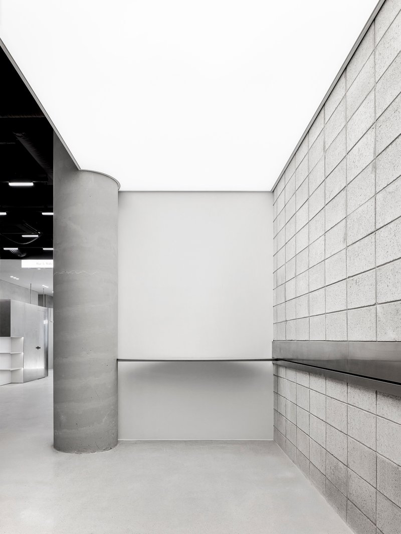 Open courtyard space framed by concrete column, gridded block wall and white recessed ceiling