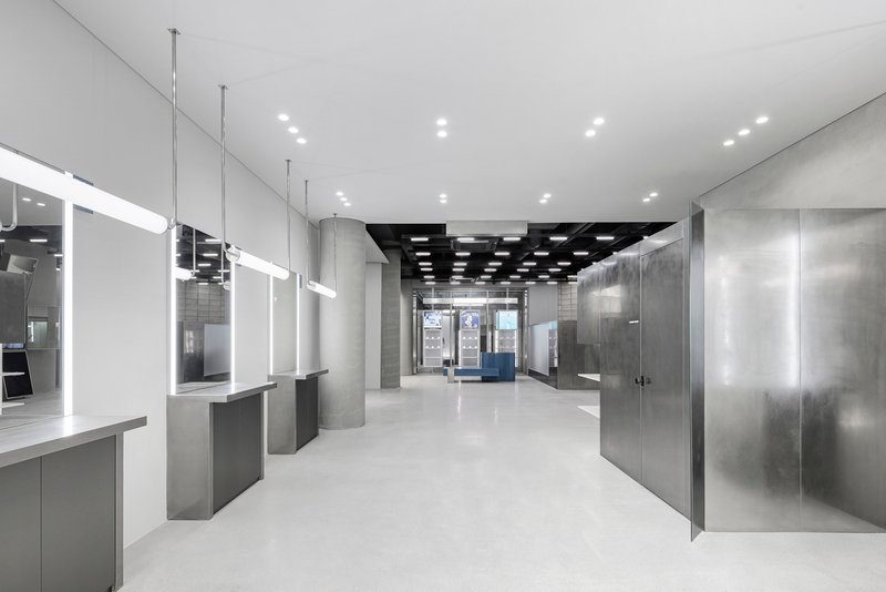 Interior retail space with suspended glass display cases, concrete walls and grid ceiling with recessed lights