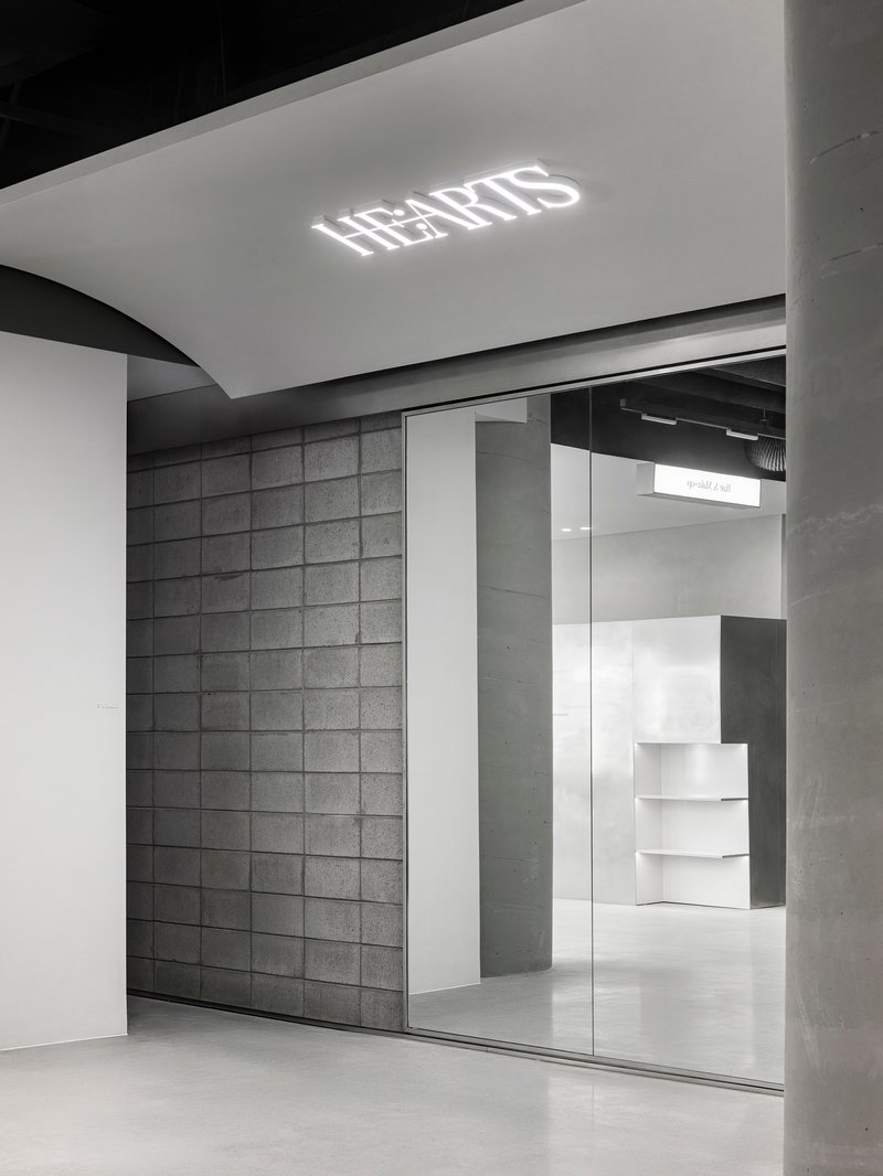 Glass storefront entrance with illuminated ceiling logo and view into retail space with white stepped displays