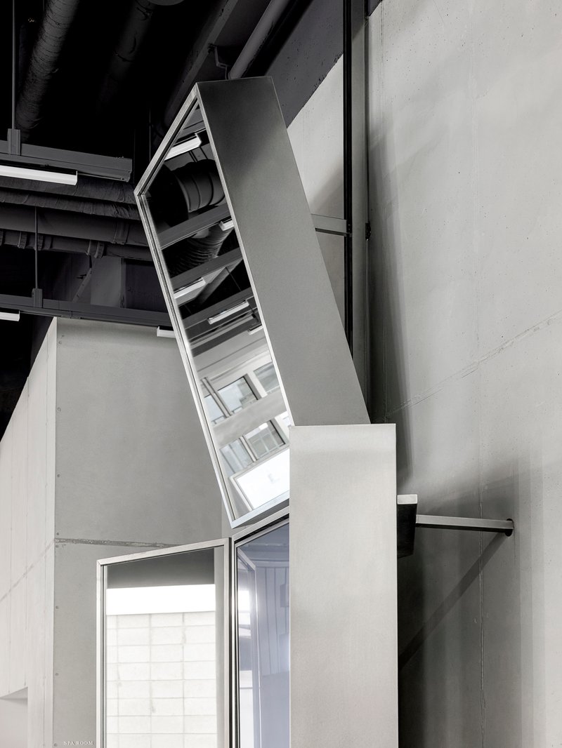 Angled skylight penetrating through white volume beneath exposed black ceiling ductwork
