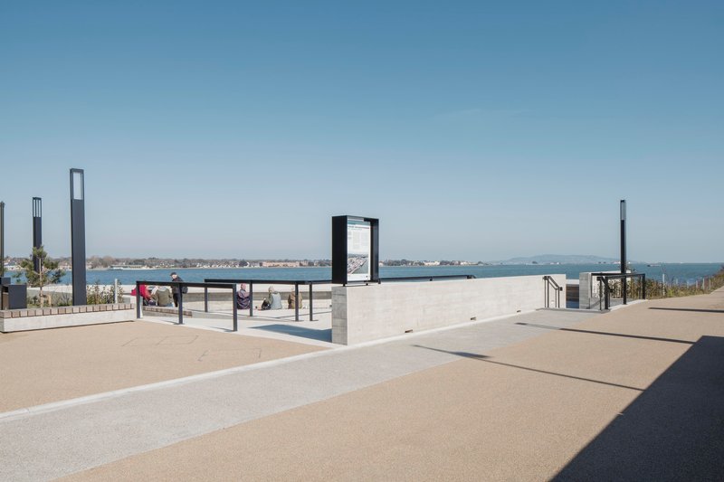 Paved plaza with information kiosks and concrete walls opening to views of the harbor