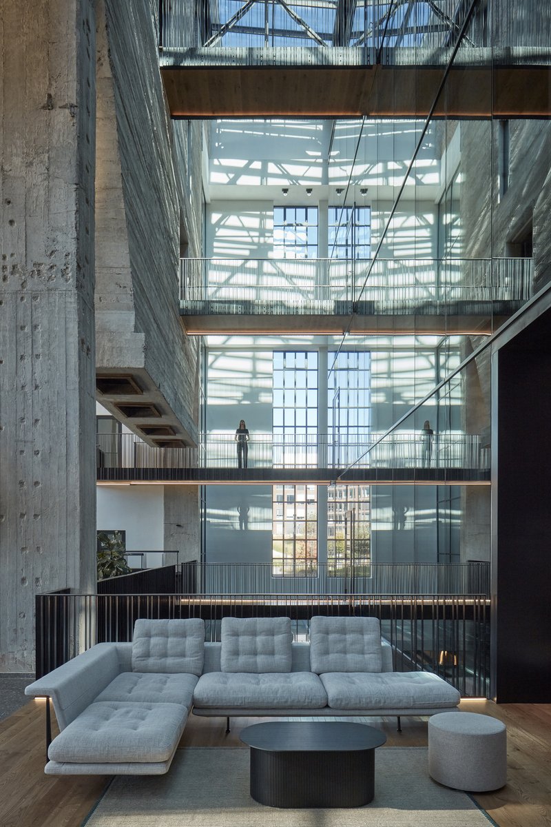 Lounge seating with sectional sofa facing a full-height atrium with walkways and a figure above