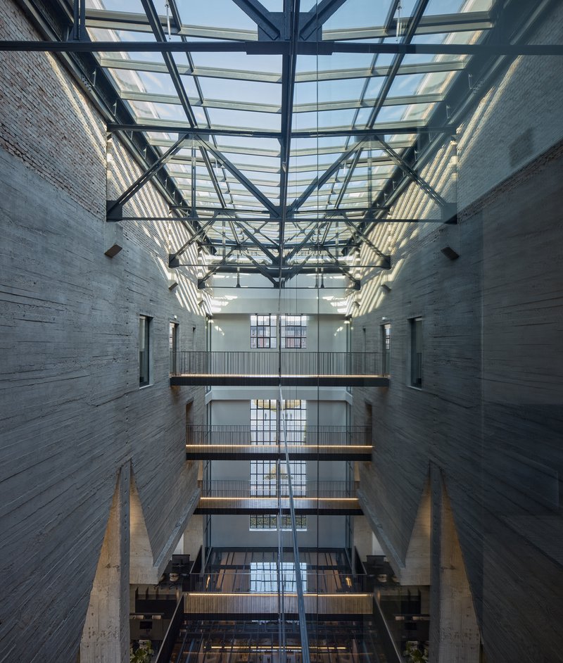 Upward view through the atrium showing stacked walkways and the steel truss skylight above