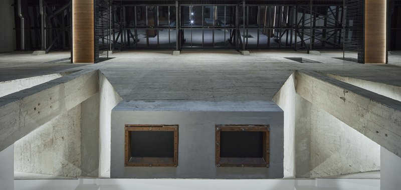Sunken concrete volume with two timber-framed openings beneath an exposed structural ceiling