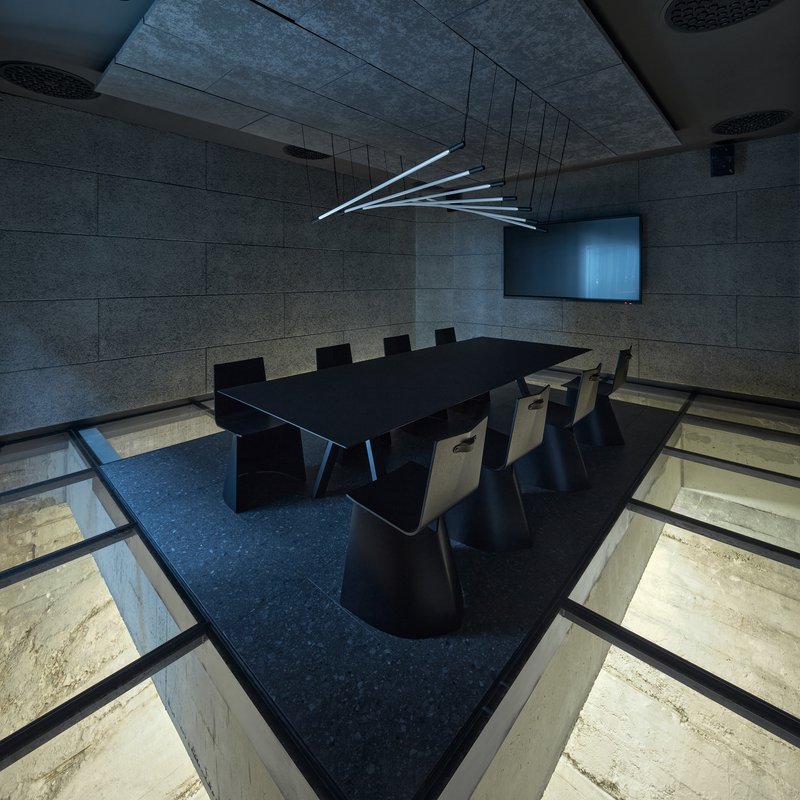 Conference room with glass floor panels revealing lower level space and linear LED fixture overhead
