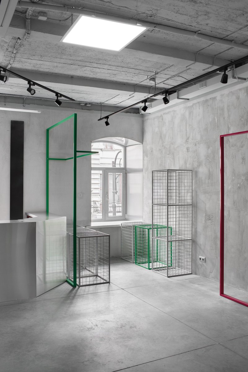 Minimal industrial showroom with modular metal display frames and exposed concrete finishes.