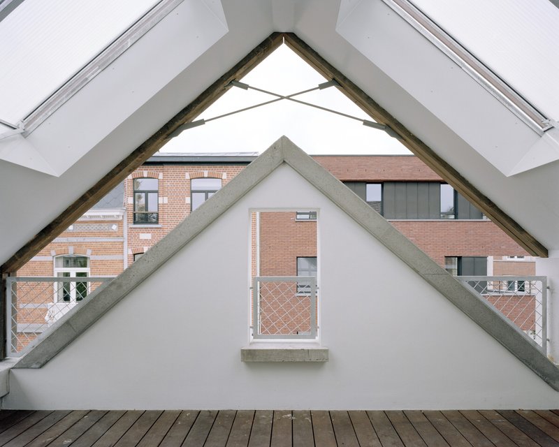 Exposed timber roof truss framing a gable window overlooking a brick courtyard
