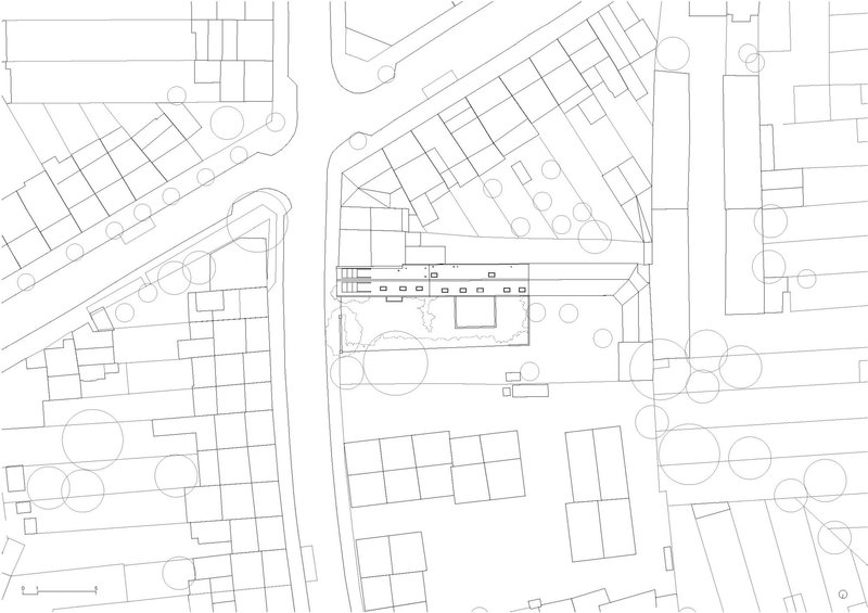 Site plan drawing showing triangular plot with building footprint and surrounding street pattern and trees