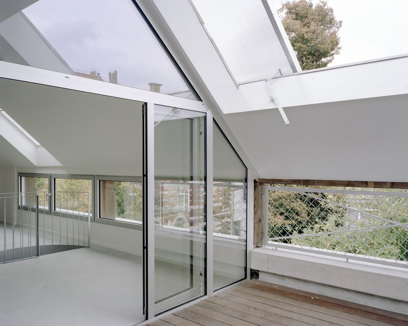 Roof terrace with timber decking, glazed sliding doors and wire mesh balustrade overlooking greenery
