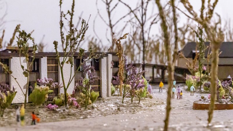 Physical model detail showing courtyard with scale figures and cherry blossom trees among residential blocks