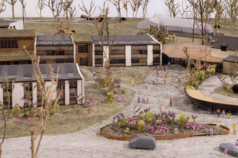 Overhead view of the physical model showing clustered housing blocks around a central courtyard with planting beds