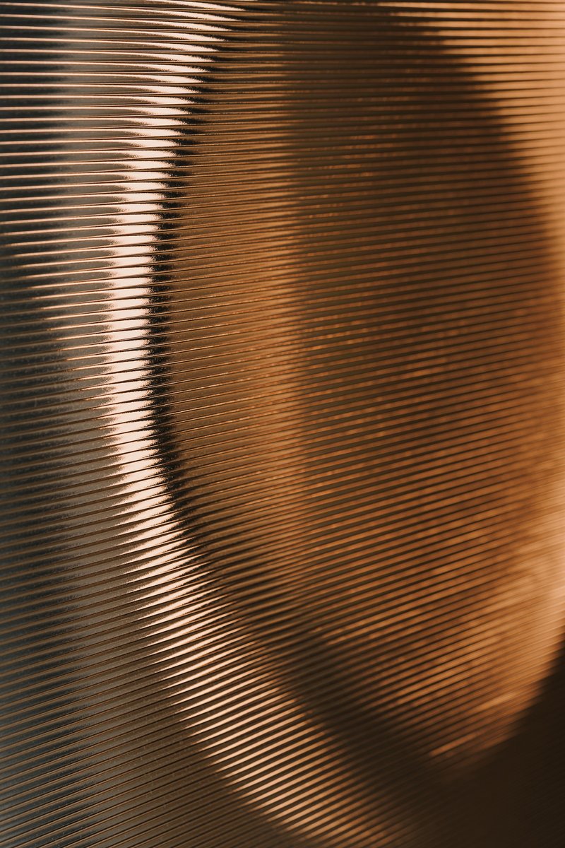 Close-up of corrugated metallic screen with horizontal ribbing catching warm afternoon light