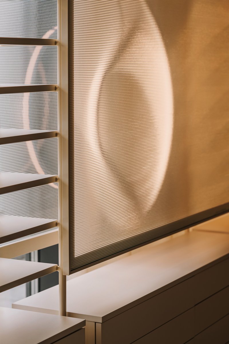 Shadow cast on ribbed translucent wall beside white display ledge in daylight