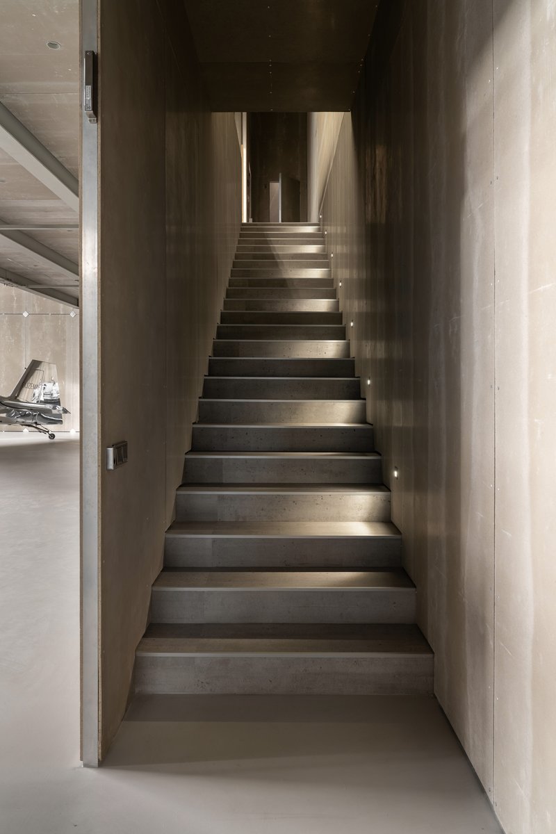 Narrow concrete stairwell with integrated step lighting ascending between dark walls