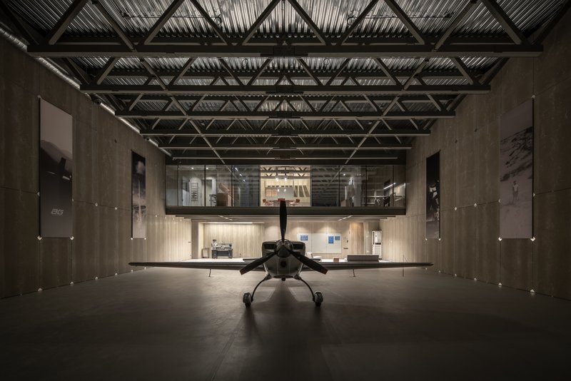Tail view of aircraft centered in the hangar with mezzanine level visible at the rear