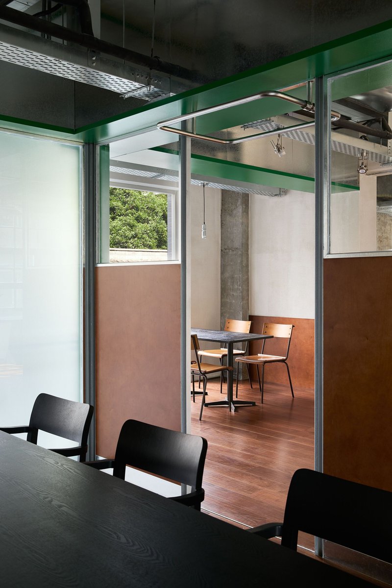 Seating booth framed by steel posts and glass partition with copper-clad lower wall panels