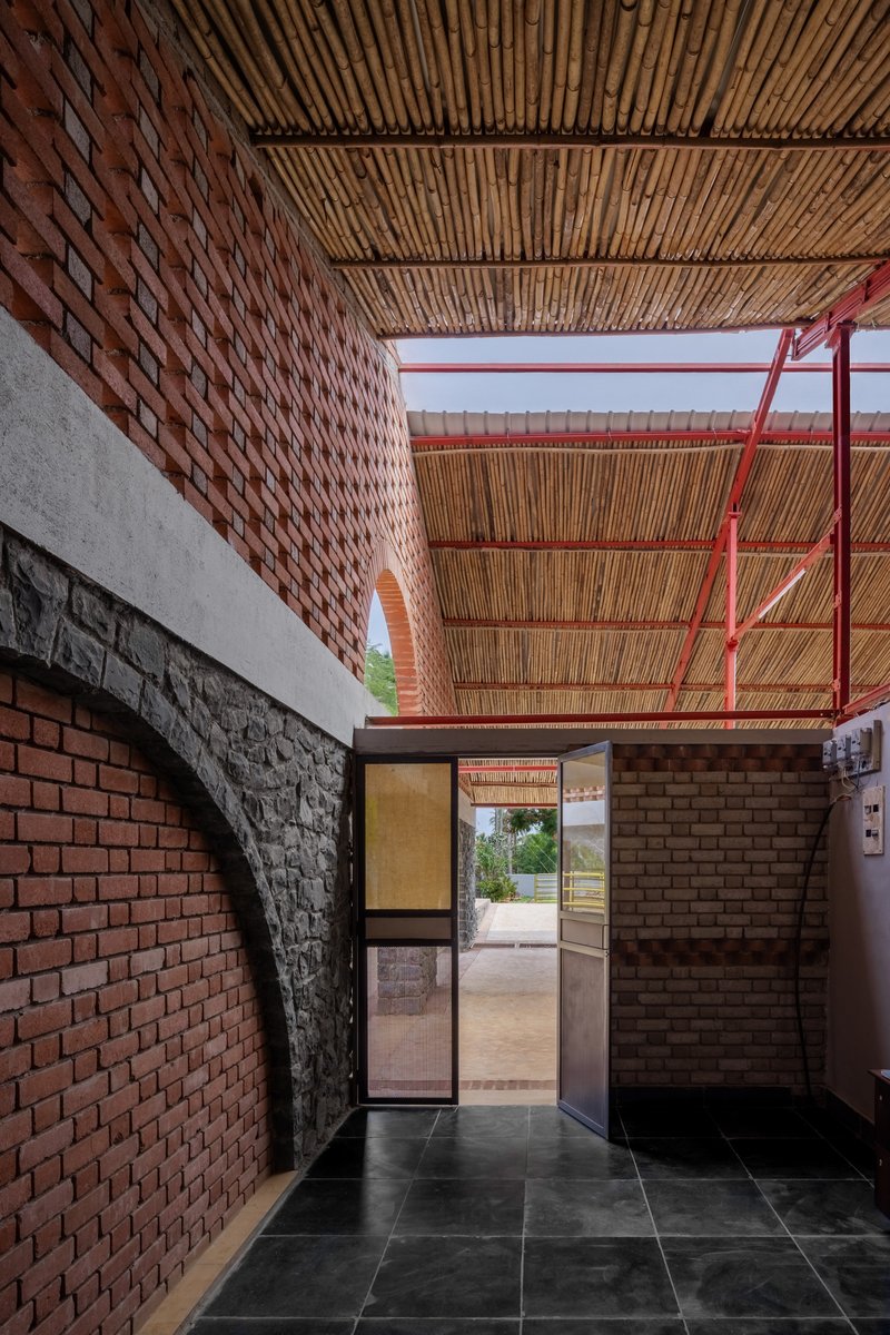Doorway framed by perforated brick walls and bamboo ceiling with red steel structure above