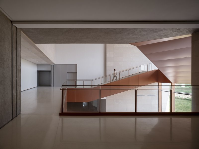 Curved copper-clad ramp crossing a double-height space with a person ascending the upper level